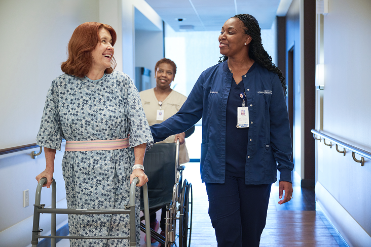 Nurse assisting patient with walk through hall