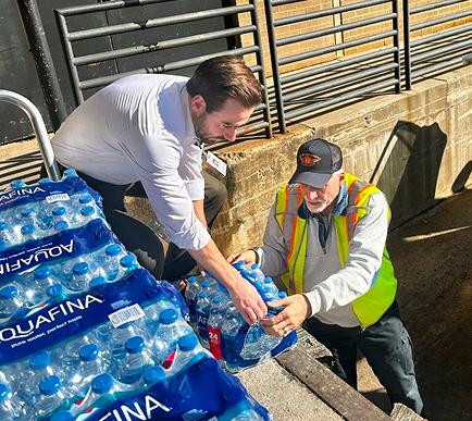 Two people moving large packs of water.